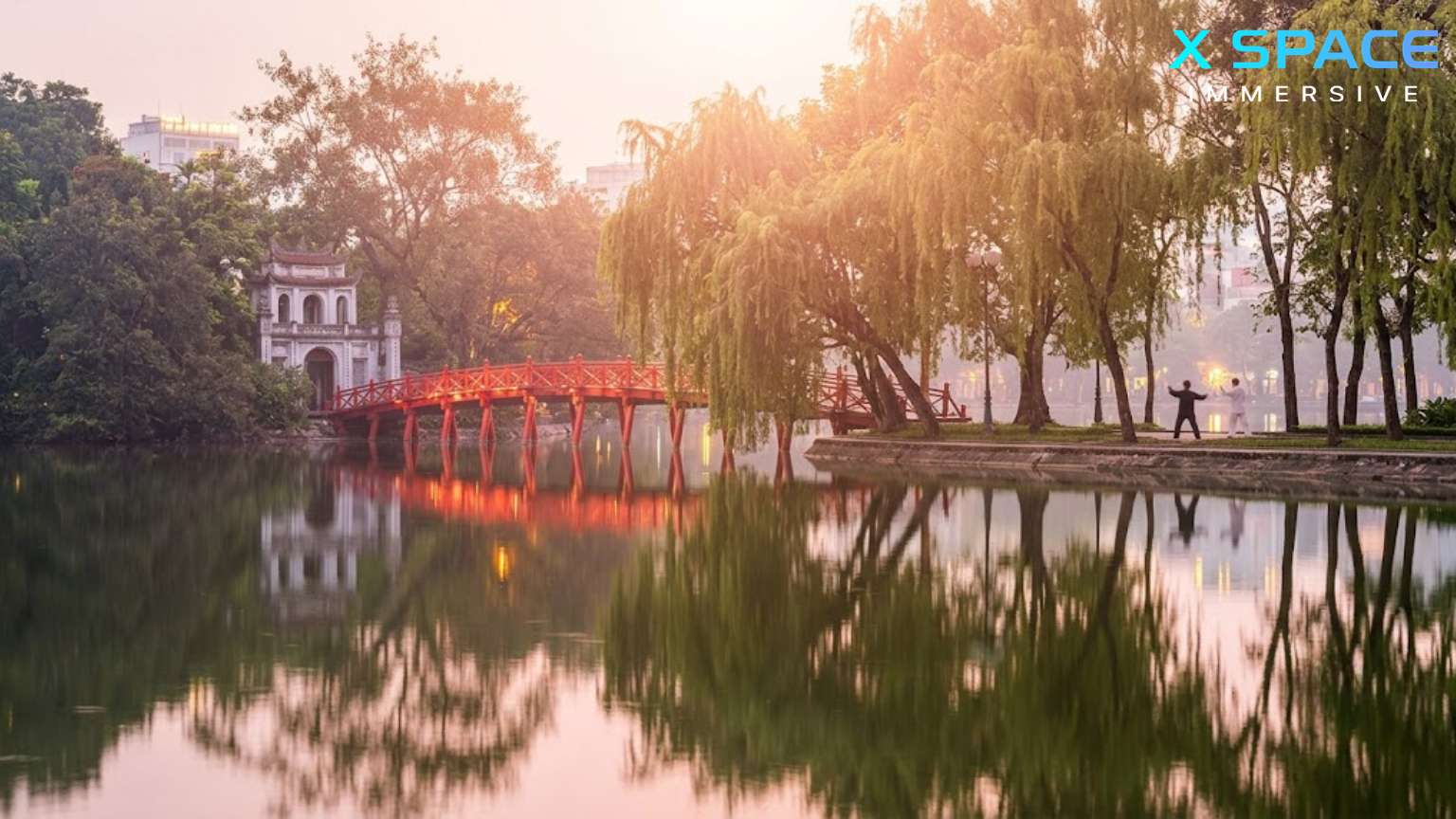 A serene dawn at Hoan Kiem Lake, Hanoi, featuring the famous red Huc Bridge and willow trees