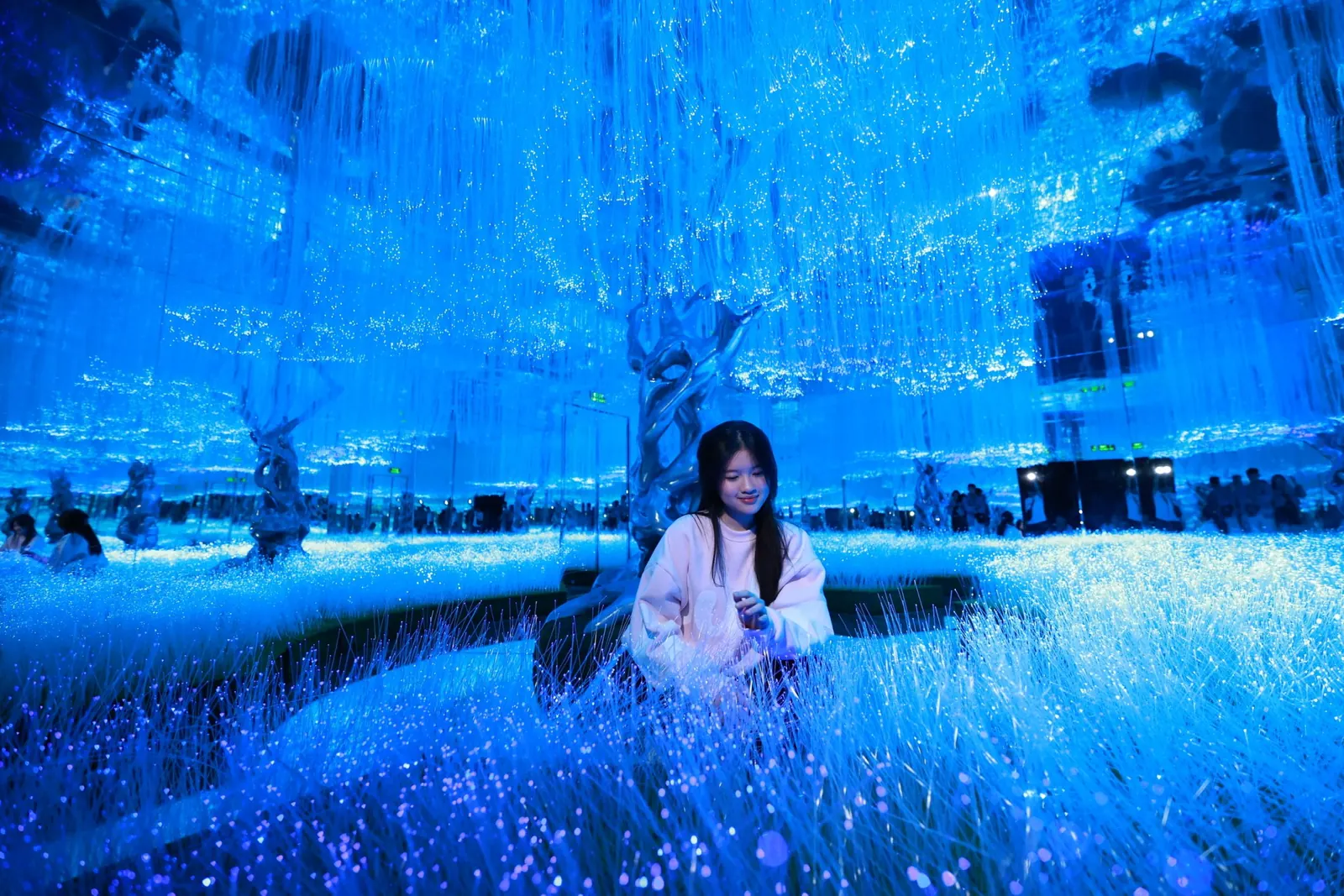 A visitor among the glowing fibre-optic grass in the Light Forest room at X Space Immersive, Hanoi