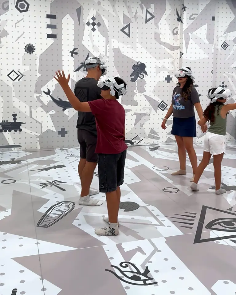 A family wearing VR headsets moving around the VR room at X Space Immersive, Royal City, Hanoi