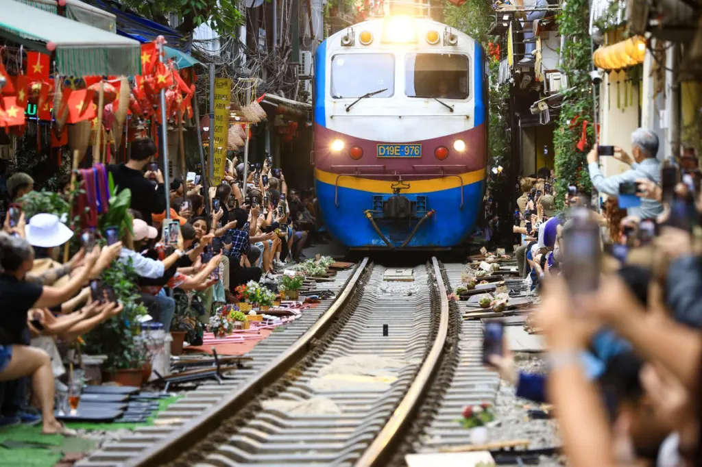Đoàn tàu chạy sát hai hàng khách giơ điện thoại quay trên phố đường tàu ở Hà Nội